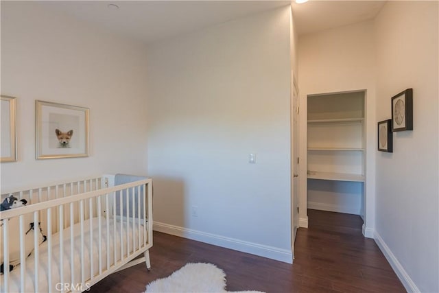 bedroom featuring a crib and dark wood-type flooring