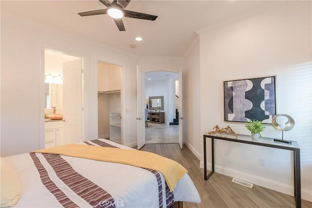 bedroom featuring ensuite bathroom, ornamental molding, a spacious closet, ceiling fan, and light hardwood / wood-style flooring