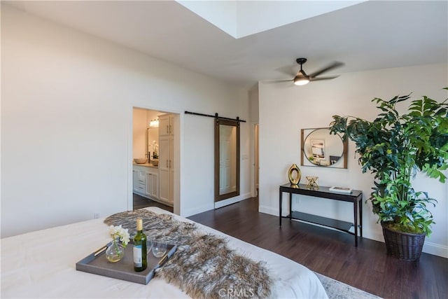 bedroom with ensuite bathroom, a barn door, and dark hardwood / wood-style flooring