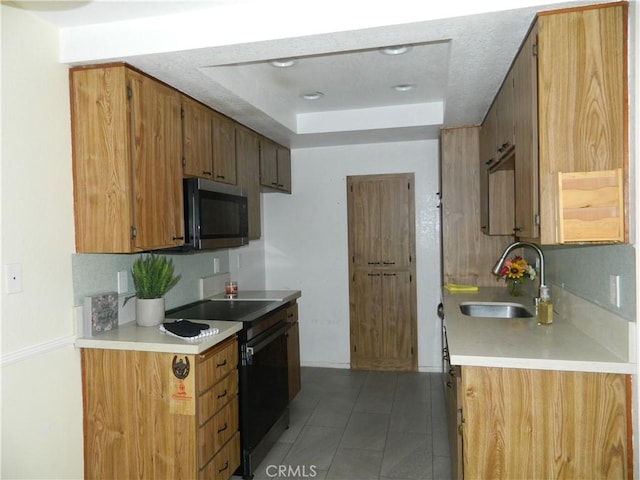 kitchen featuring a tray ceiling, dark tile patterned flooring, sink, and electric range