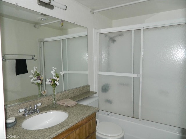 full bathroom featuring enclosed tub / shower combo, vanity, and toilet