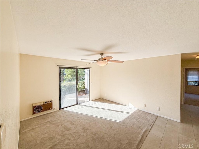 spare room featuring light carpet, ceiling fan, a textured ceiling, and heating unit