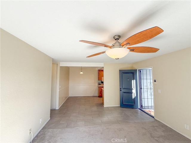 entrance foyer with a ceiling fan, light colored carpet, and baseboards