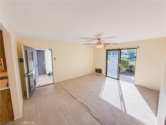 spare room with light carpet, ceiling fan, and a textured ceiling