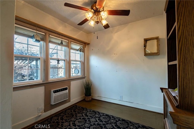 empty room with crown molding, a textured ceiling, a wall unit AC, hardwood / wood-style flooring, and ceiling fan