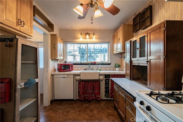 kitchen with tile countertops, sink, white appliances, ceiling fan, and a textured ceiling