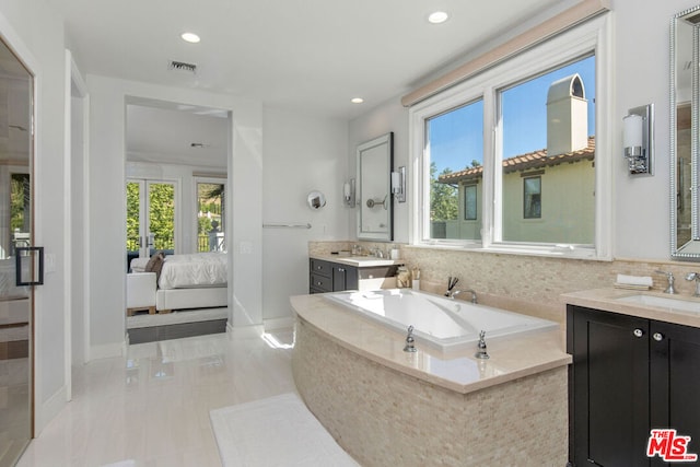 bathroom with vanity and tiled bath