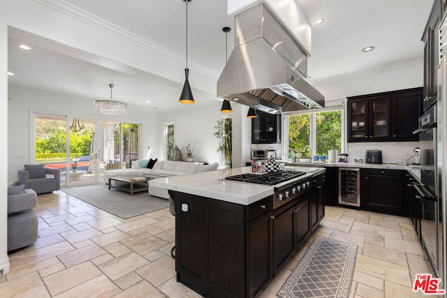 kitchen with a kitchen island, island range hood, pendant lighting, wine cooler, and stainless steel gas cooktop