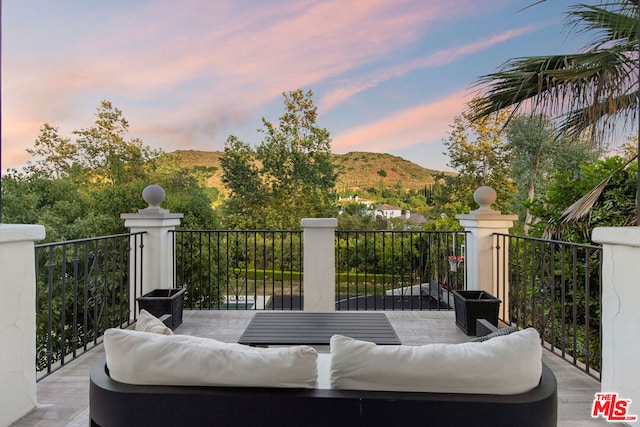 patio terrace at dusk with a balcony, an outdoor hangout area, and a mountain view