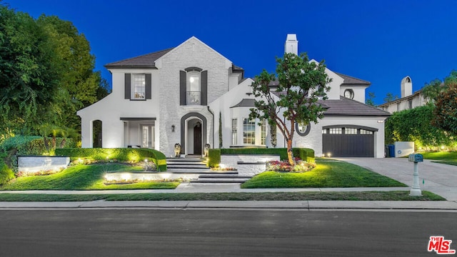 french country style house featuring a garage and a lawn