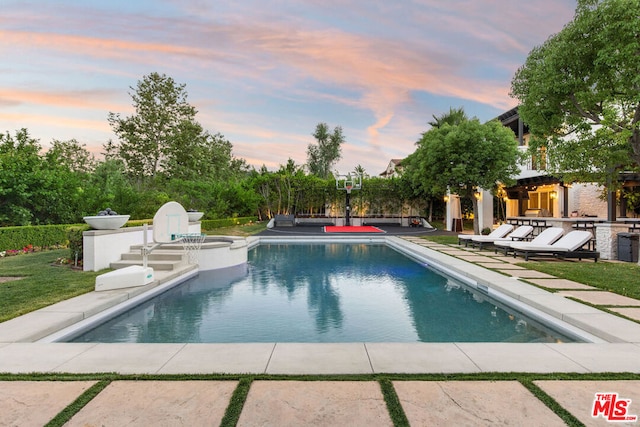 pool at dusk with a patio area