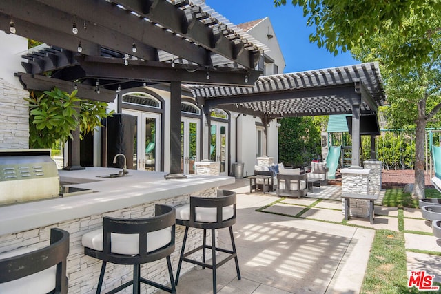 view of patio featuring a pergola, an outdoor living space, a playground, an outdoor wet bar, and exterior kitchen