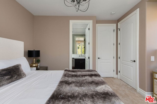 bedroom with light carpet, sink, ensuite bath, and an inviting chandelier