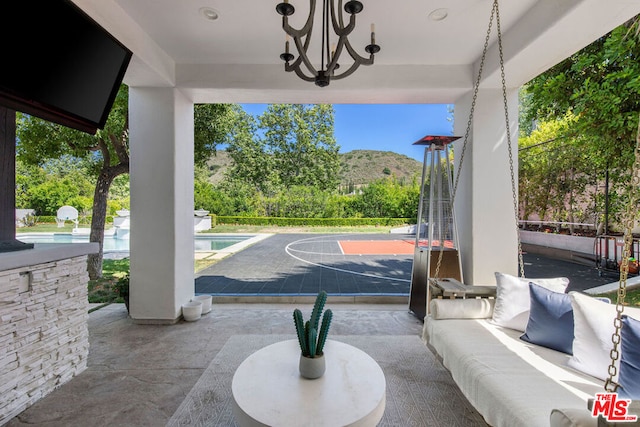 view of patio with an outdoor living space, a mountain view, and basketball hoop