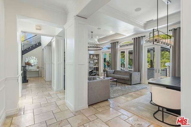 interior space with french doors, ornamental molding, a tray ceiling, and ornate columns