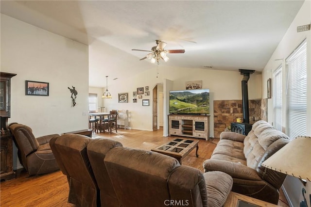 living room featuring lofted ceiling, light hardwood / wood-style floors, a healthy amount of sunlight, and a wood stove