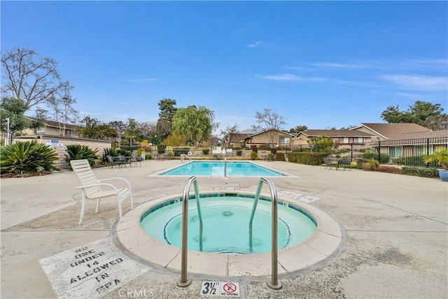 view of swimming pool with a hot tub and a patio area