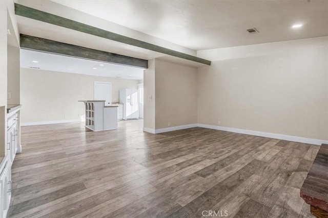 empty room featuring beamed ceiling and light hardwood / wood-style flooring