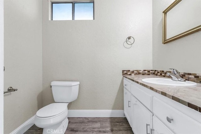 bathroom featuring hardwood / wood-style flooring, vanity, toilet, and decorative backsplash