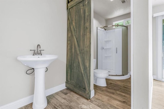 bathroom with hardwood / wood-style flooring, toilet, and walk in shower