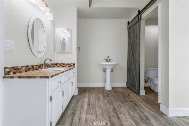 bathroom with wood-type flooring, dual sinks, backsplash, and toilet