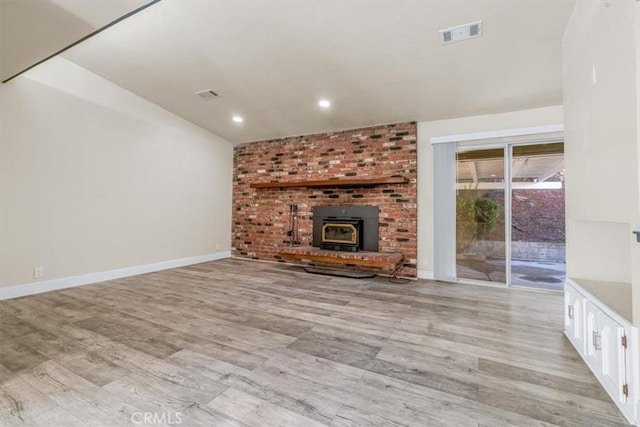 unfurnished living room with light hardwood / wood-style floors and a wood stove