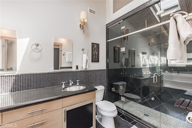 bathroom featuring walk in shower, tile patterned floors, toilet, tile walls, and vanity