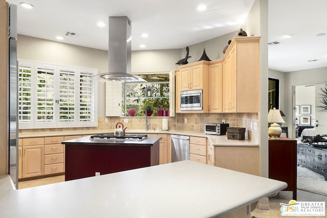 kitchen with island range hood, light brown cabinets, decorative backsplash, and appliances with stainless steel finishes