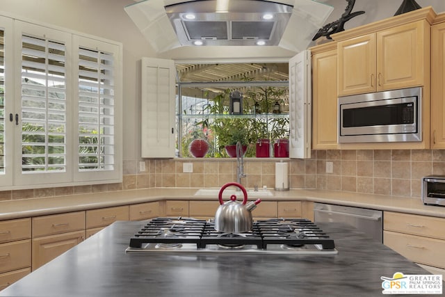 kitchen with sink, appliances with stainless steel finishes, tasteful backsplash, exhaust hood, and light brown cabinets