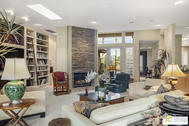 living room featuring light carpet, a fireplace, and a skylight