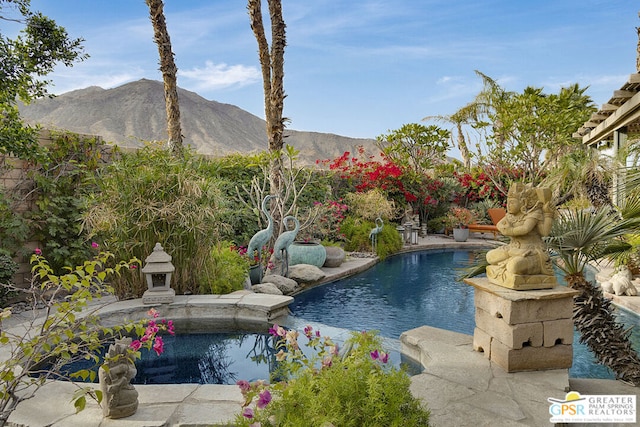 view of swimming pool featuring a mountain view, an outdoor stone fireplace, and a patio area