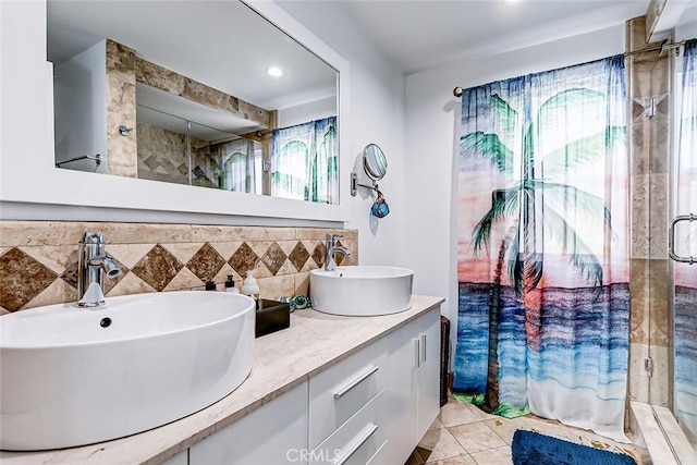 full bath with a stall shower, double vanity, a sink, and tile patterned floors