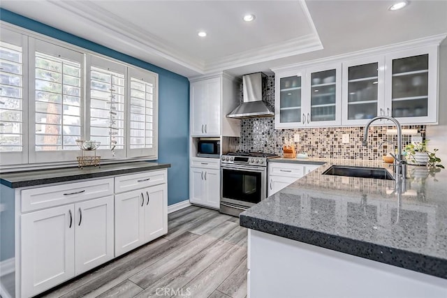 kitchen featuring white cabinetry, stainless steel appliances, sink, and wall chimney range hood