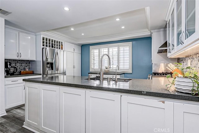 kitchen with white cabinets, crown molding, dark hardwood / wood-style flooring, dark stone counters, and stainless steel refrigerator with ice dispenser