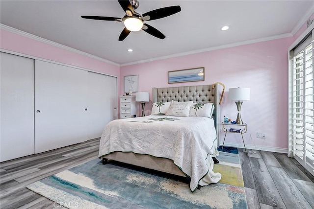 bedroom with wood finished floors, a closet, baseboards, a ceiling fan, and crown molding