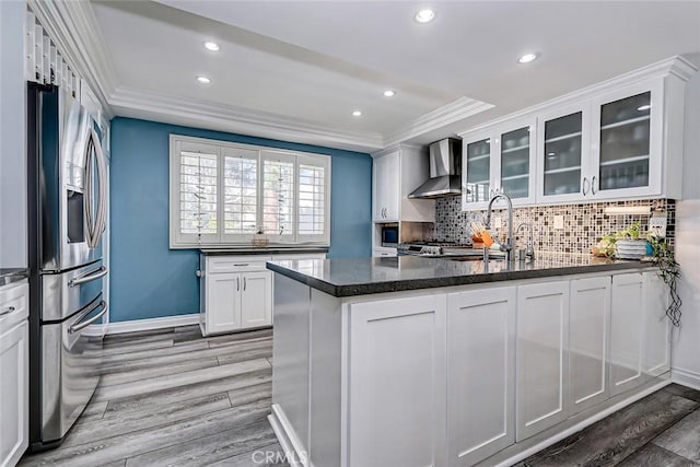 kitchen with a sink, light wood finished floors, ornamental molding, wall chimney exhaust hood, and stainless steel refrigerator with ice dispenser