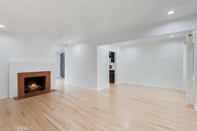 unfurnished living room featuring a fireplace and light hardwood / wood-style floors