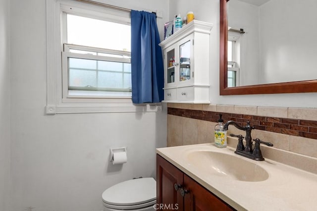 bathroom featuring vanity, toilet, and backsplash