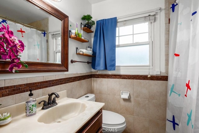 bathroom featuring vanity, tile walls, and toilet