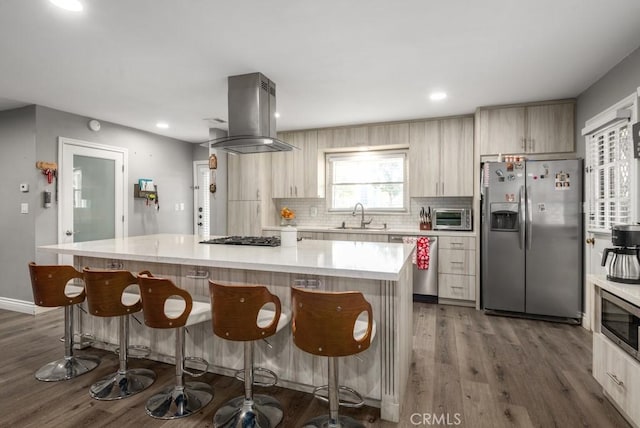 kitchen with stainless steel appliances, island exhaust hood, a center island, and sink