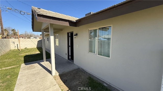 property entrance with a lawn and a patio area