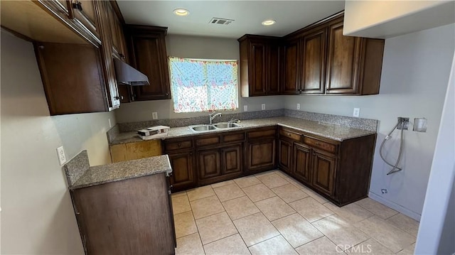 kitchen with sink, light tile patterned floors, and dark brown cabinets