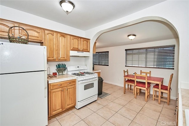 kitchen with light tile patterned floors, white appliances, and tile counters