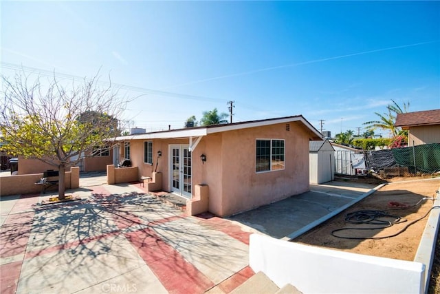 view of front of property featuring french doors, a shed, and a patio