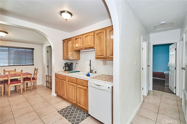 kitchen featuring dishwasher, sink, light tile patterned floors, and tile counters