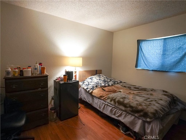 bedroom with hardwood / wood-style floors and a textured ceiling