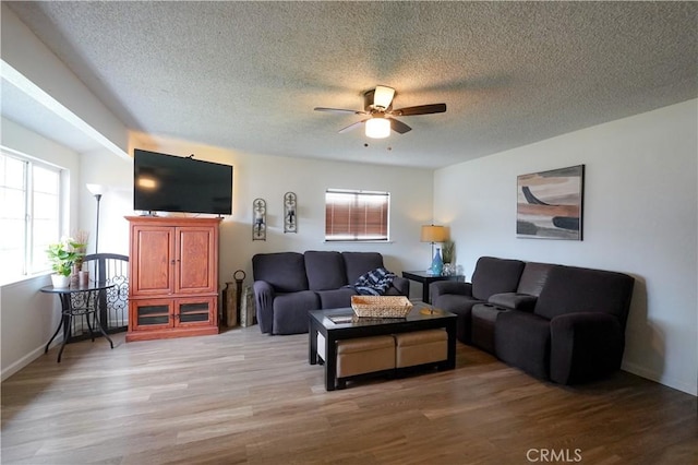 living room featuring hardwood / wood-style flooring, ceiling fan, and a textured ceiling