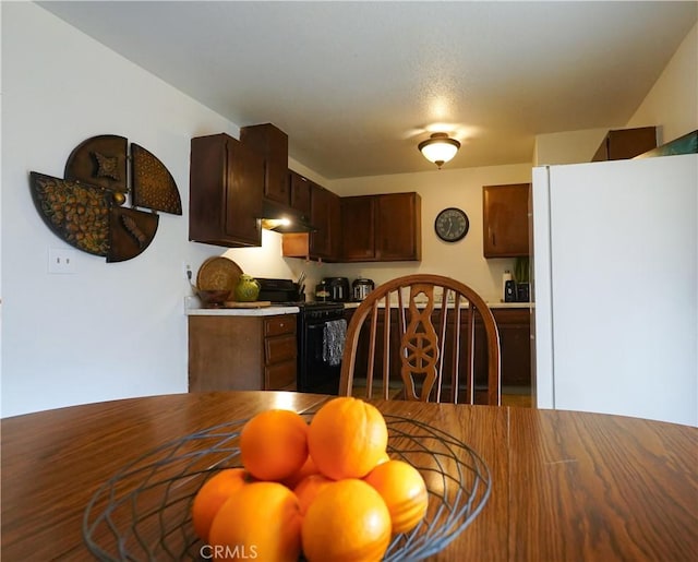 kitchen with dark brown cabinetry, black range with gas cooktop, and white fridge