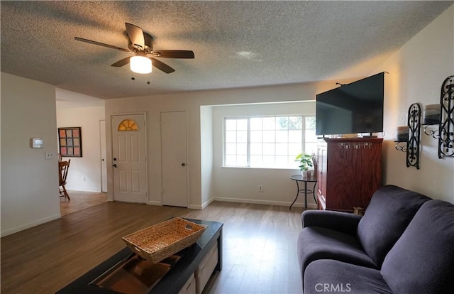 living room featuring ceiling fan, a textured ceiling, and light wood-type flooring