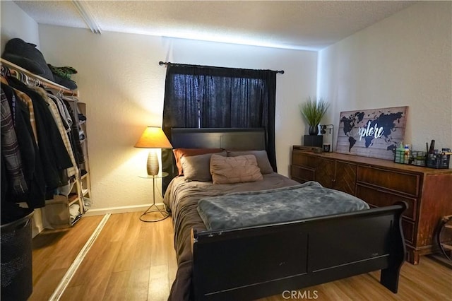 bedroom with a textured ceiling and light hardwood / wood-style flooring